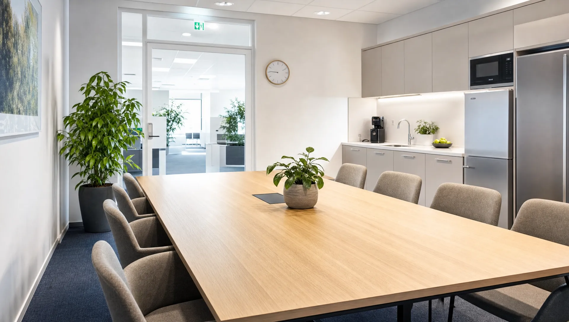Valoisa ja siisti toimiston neuvotteluhuone, jossa pöytä on puhdas, tuolit järjestyksessä ja taustalla näkyy huoliteltu keittiötila sekä raikas yleisilme.